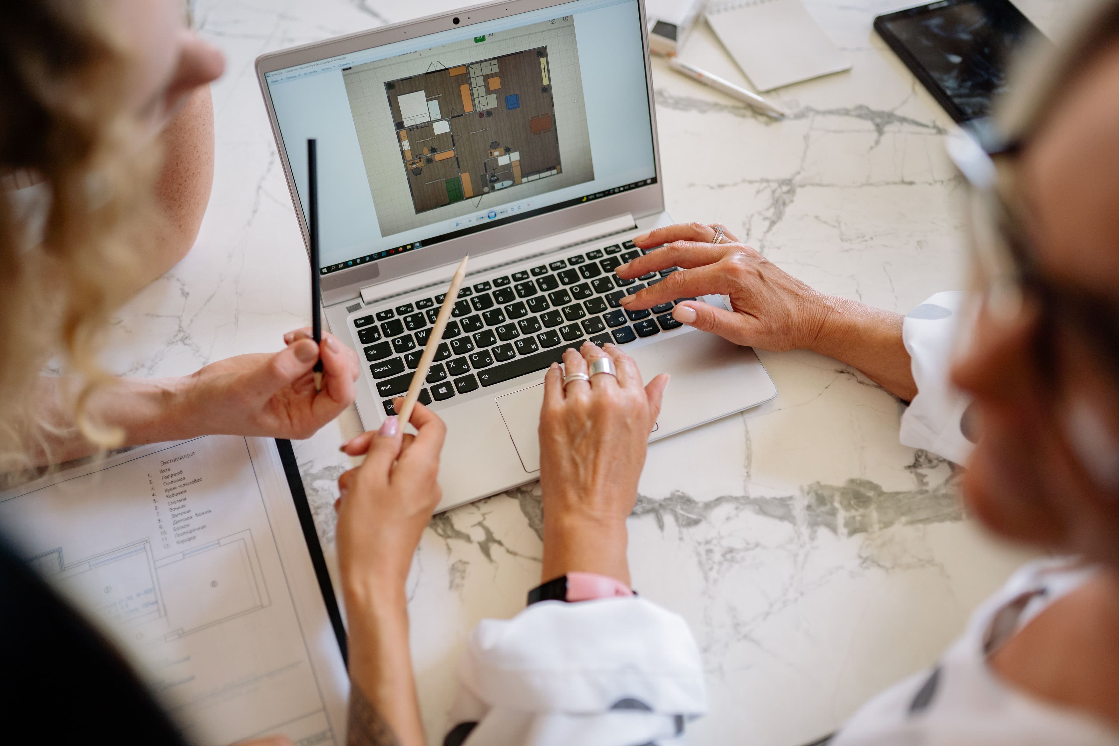 People collaborating around a laptop and printed working documents